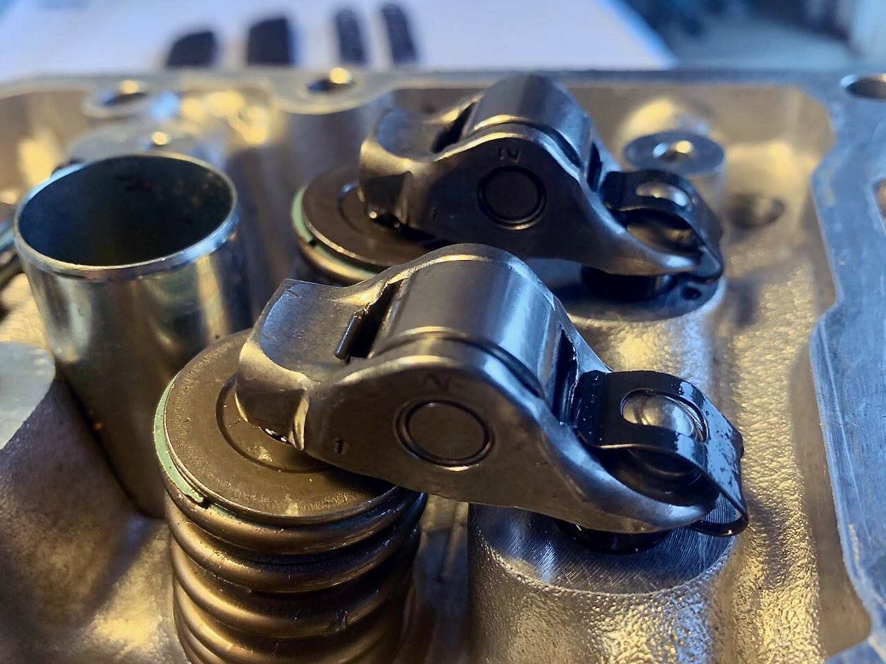 Close-up of Denstoj FA/FB Subaru rocker retainers installed on a cylinder head, showing the rocker arms positioned over valve springs (without camshafts).