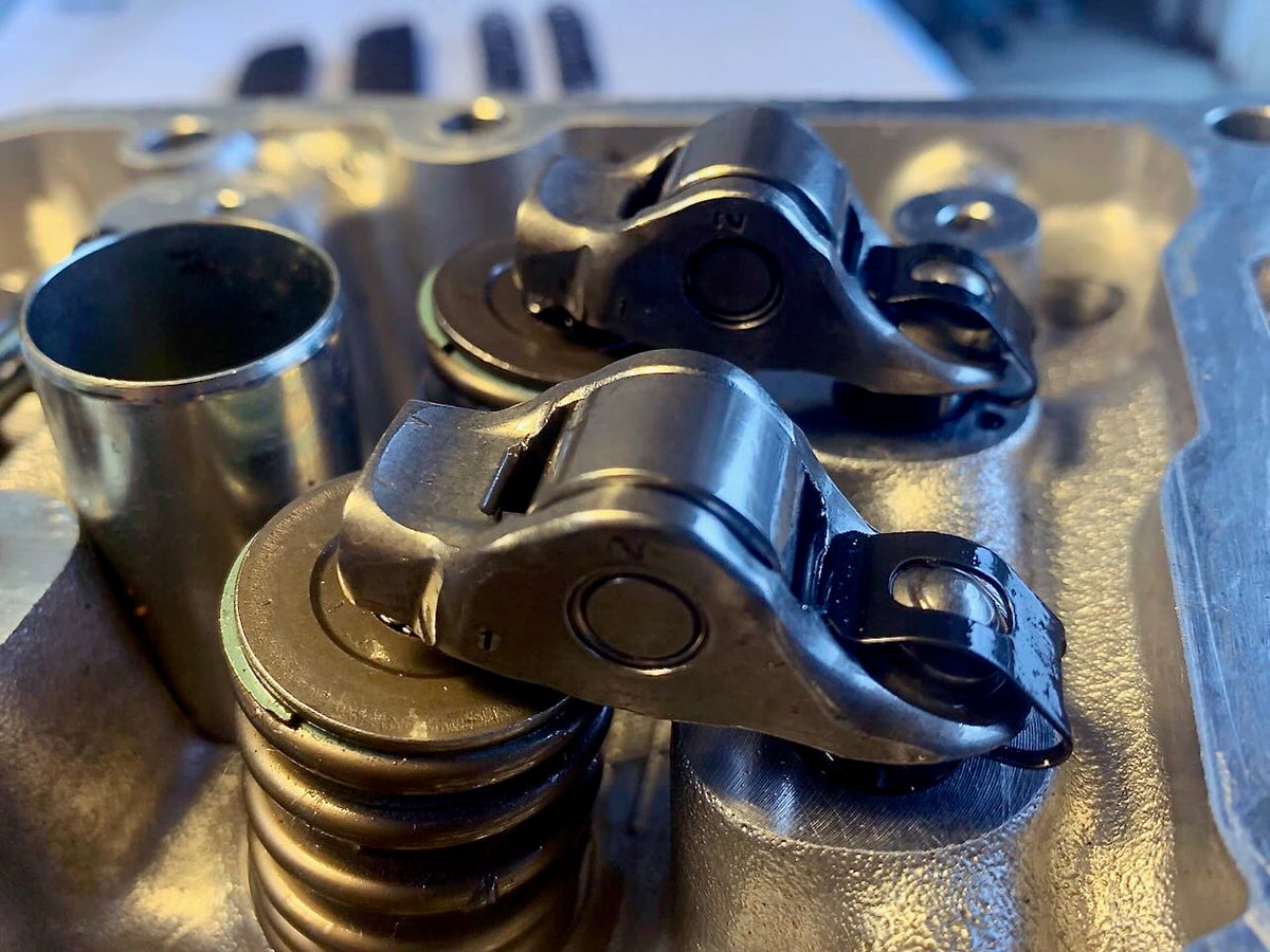 Close-up of Denstoj FA/FB Subaru rocker retainers installed on a cylinder head, showing the rocker arms positioned over valve springs (without camshafts).