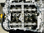 Overhead view of a Subaru FA24 cylinder head with camshafts and Denstoj FA/FB rocker retainers installed, showing the assembled valvetrain components, rocker arms, and valve springs.