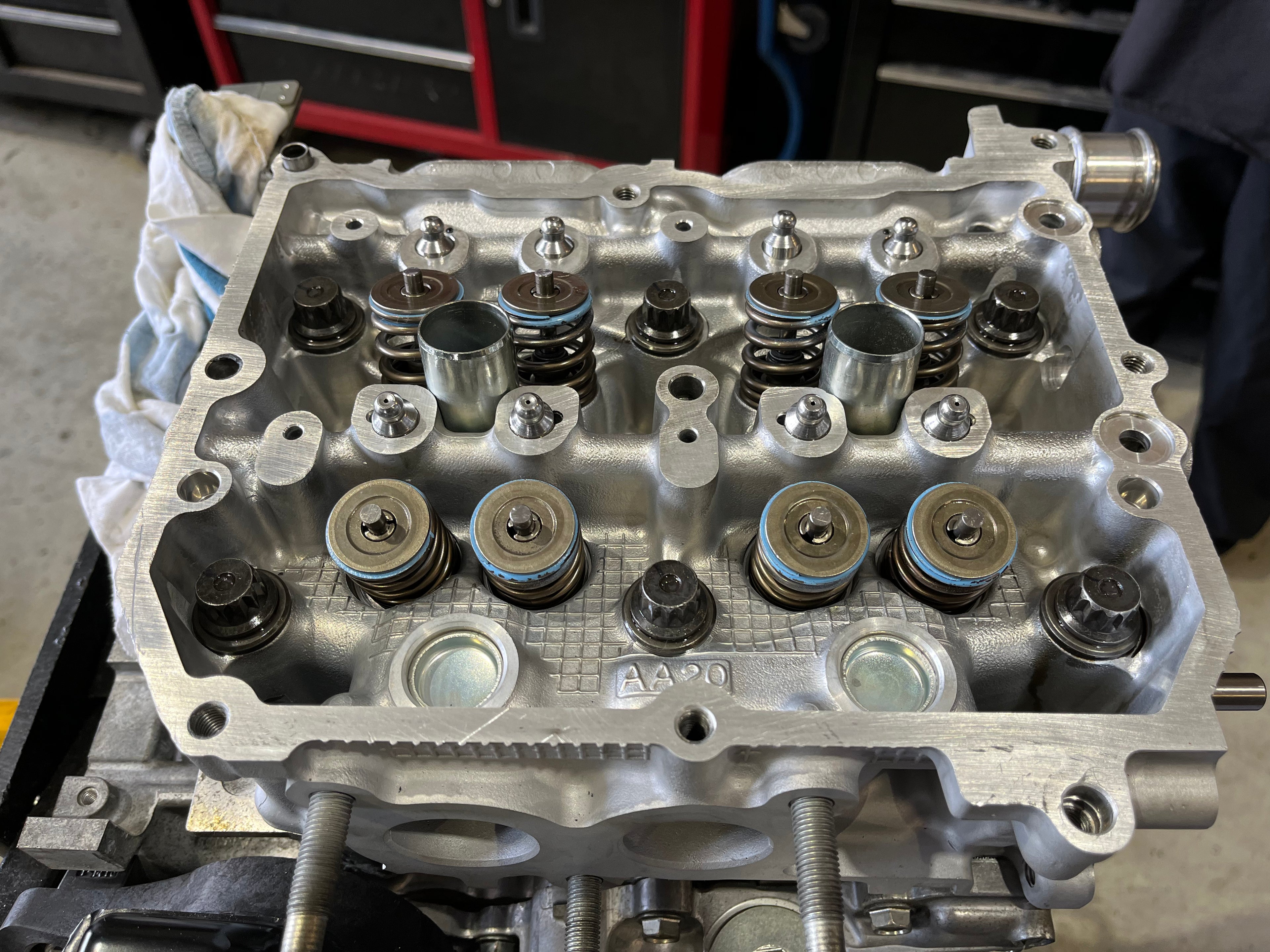 Close-up of a Subaru FA/FB cylinder head with Denstoj rocker retainer pivots installed, showing valve springs, machined aluminium head surfaces, and valvetrain components before rocker arm installation.
